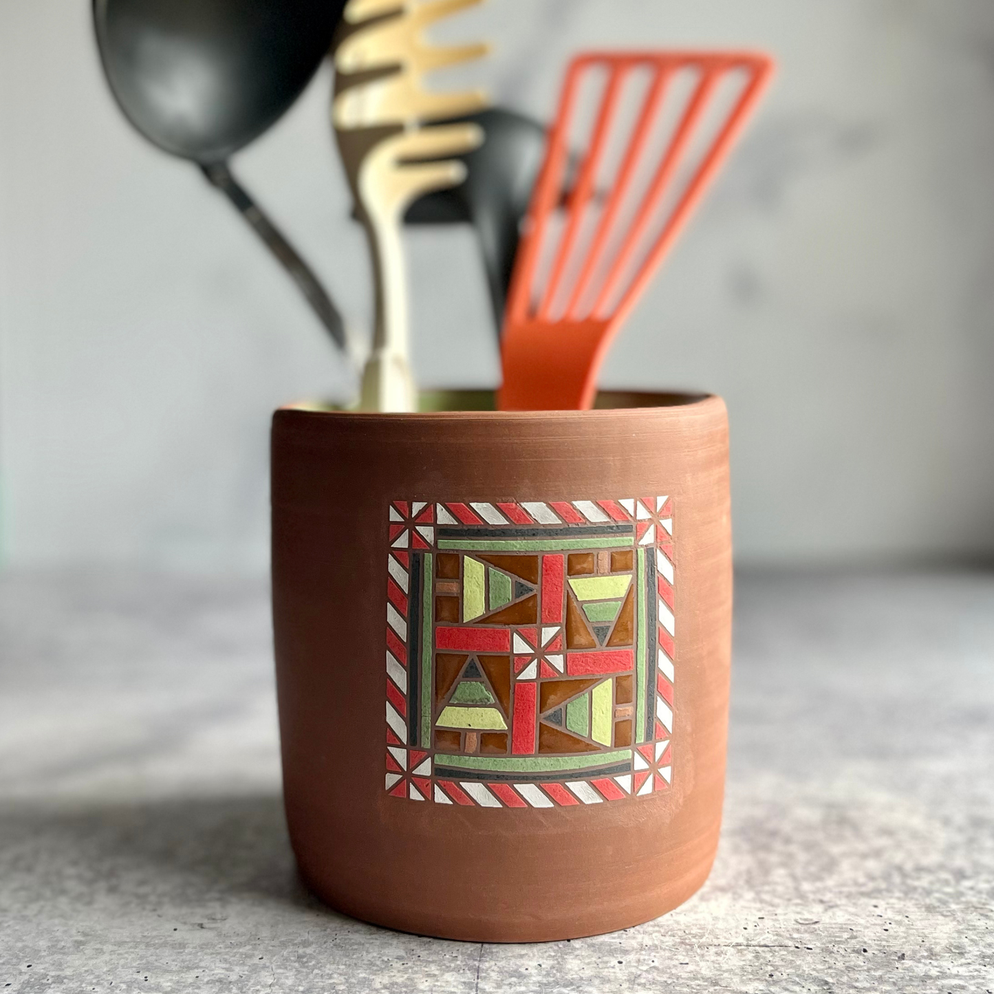 Ceramic utensil holder with geometric design on a neutral background