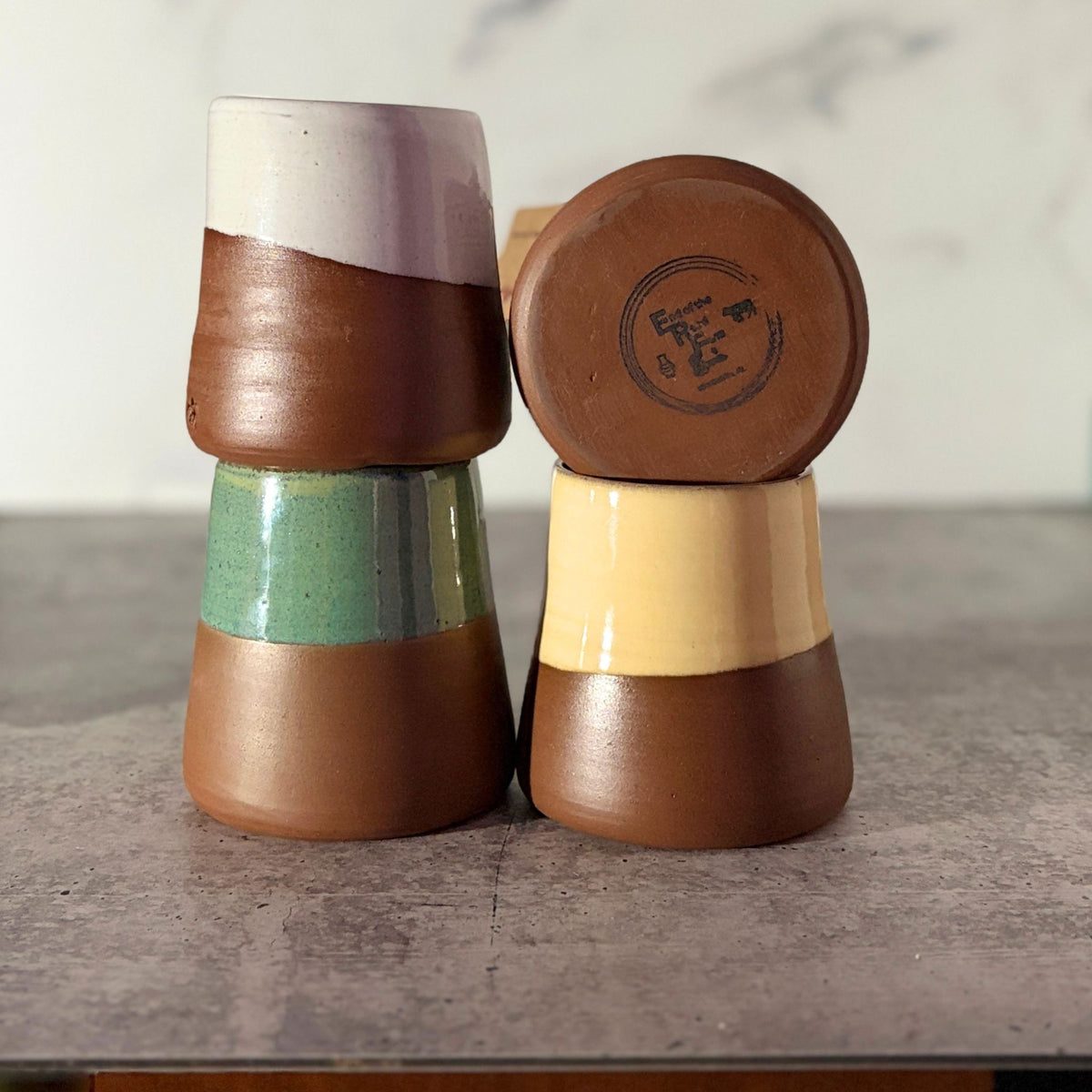 4 cone shaped bud vases in white, turquoise, green and yellow,  stacked. Bottom of turquoise is showing makers stamp
