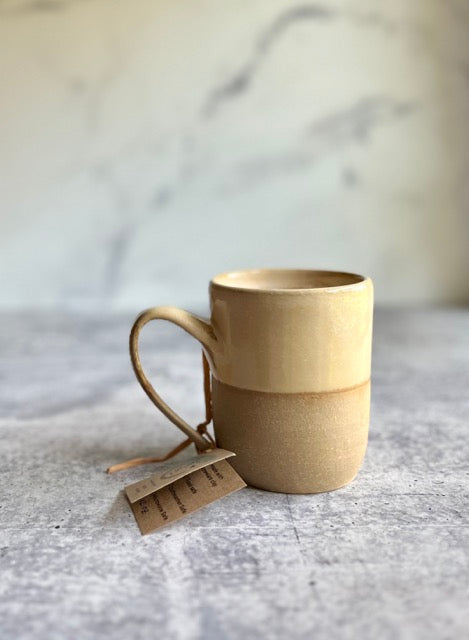 Creame ceramic mug with a tea bag on a marble surface