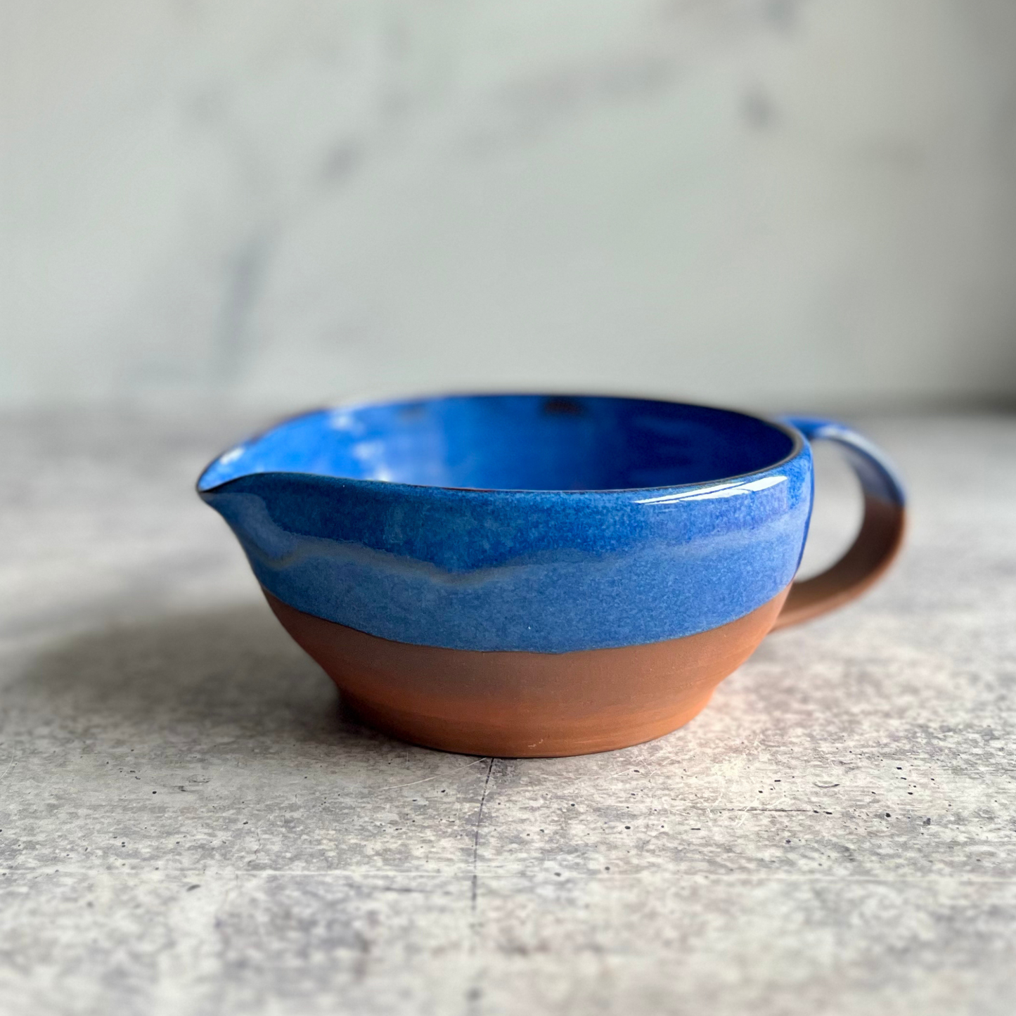Ceramic mixing bowl with blue top and brown bottom on a gray surface