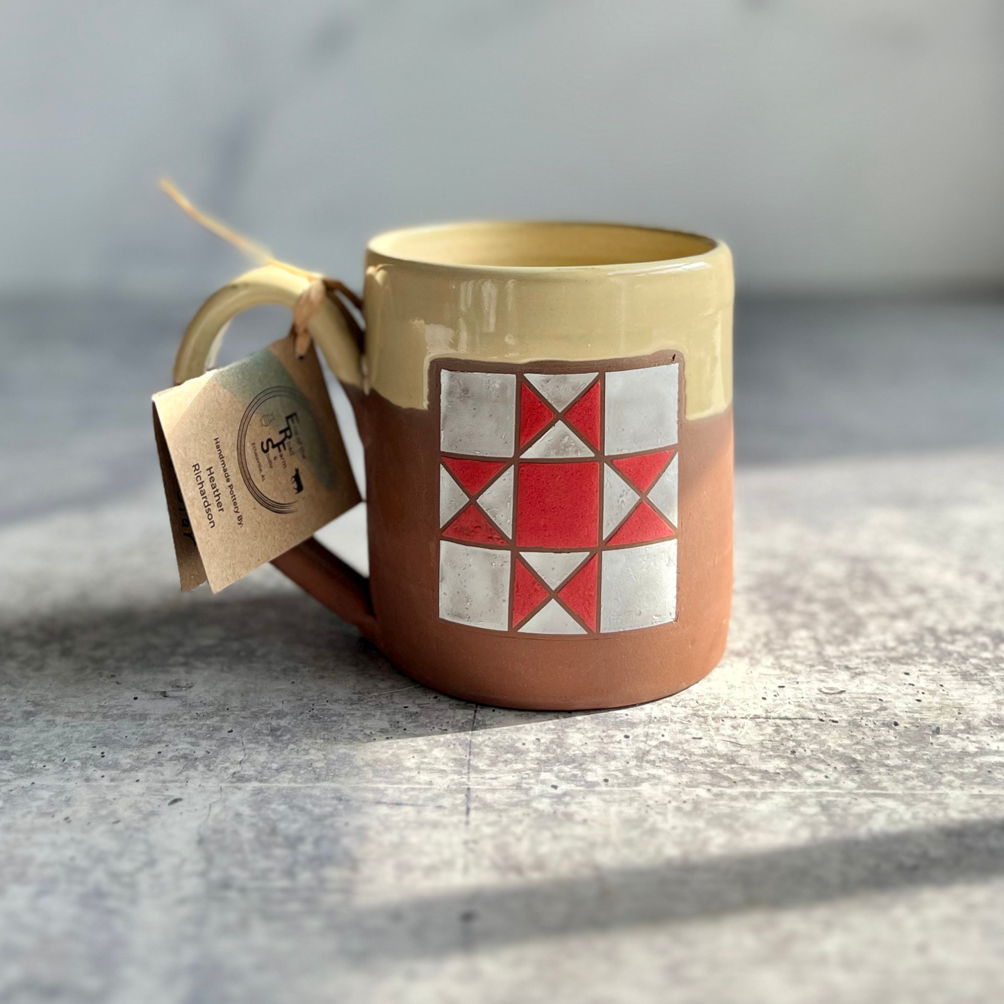 Ceramic mug with geometric design and tag on a textured surface