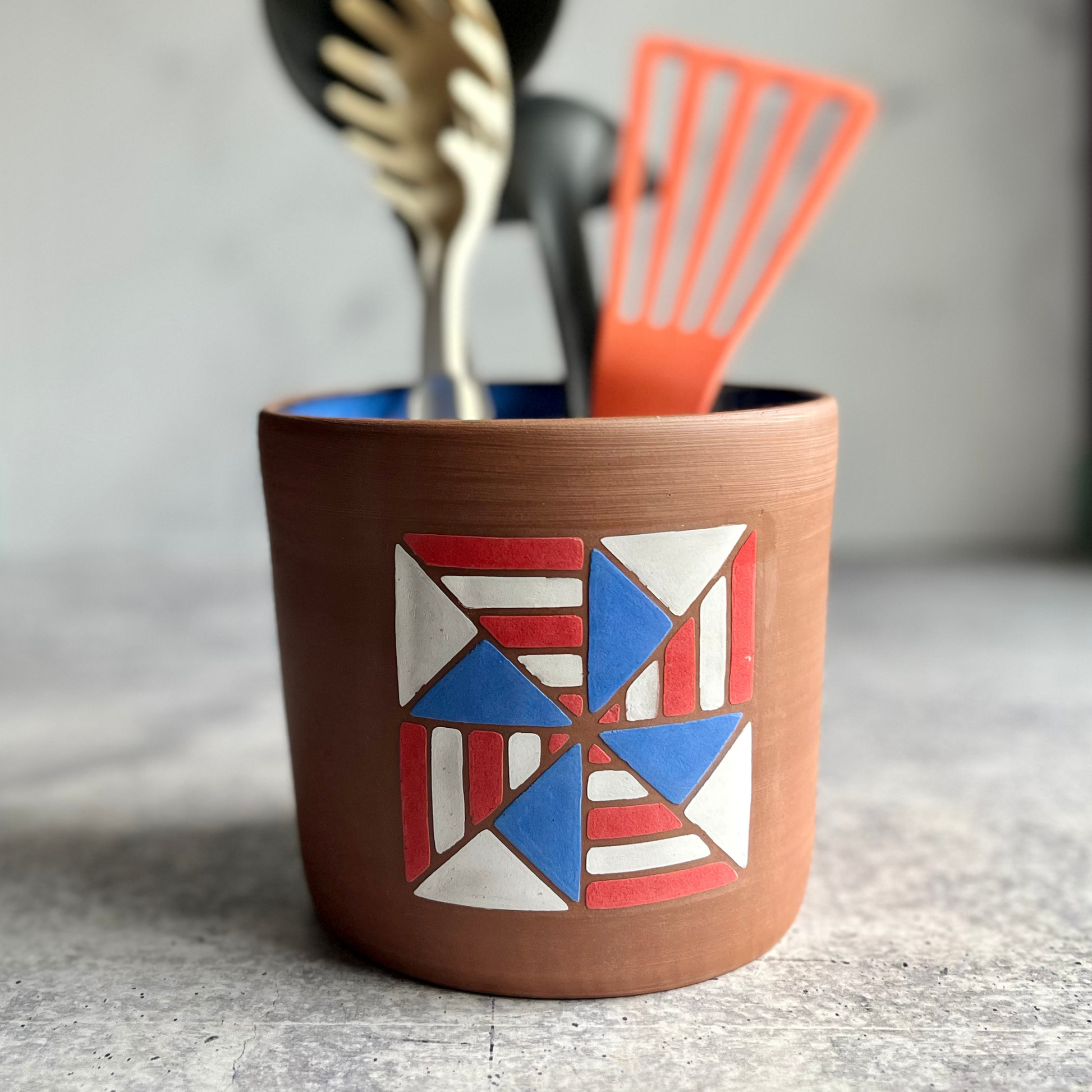 Ceramic utensil holder with geometric design on a neutral background