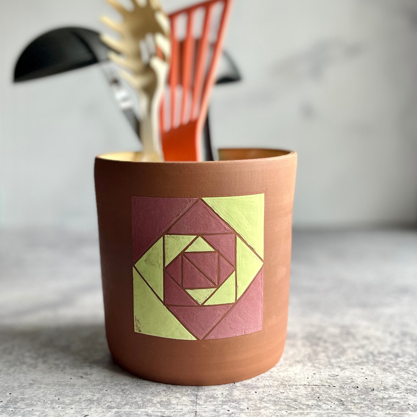 Ceramic utensil holder with geometric design on a textured surface