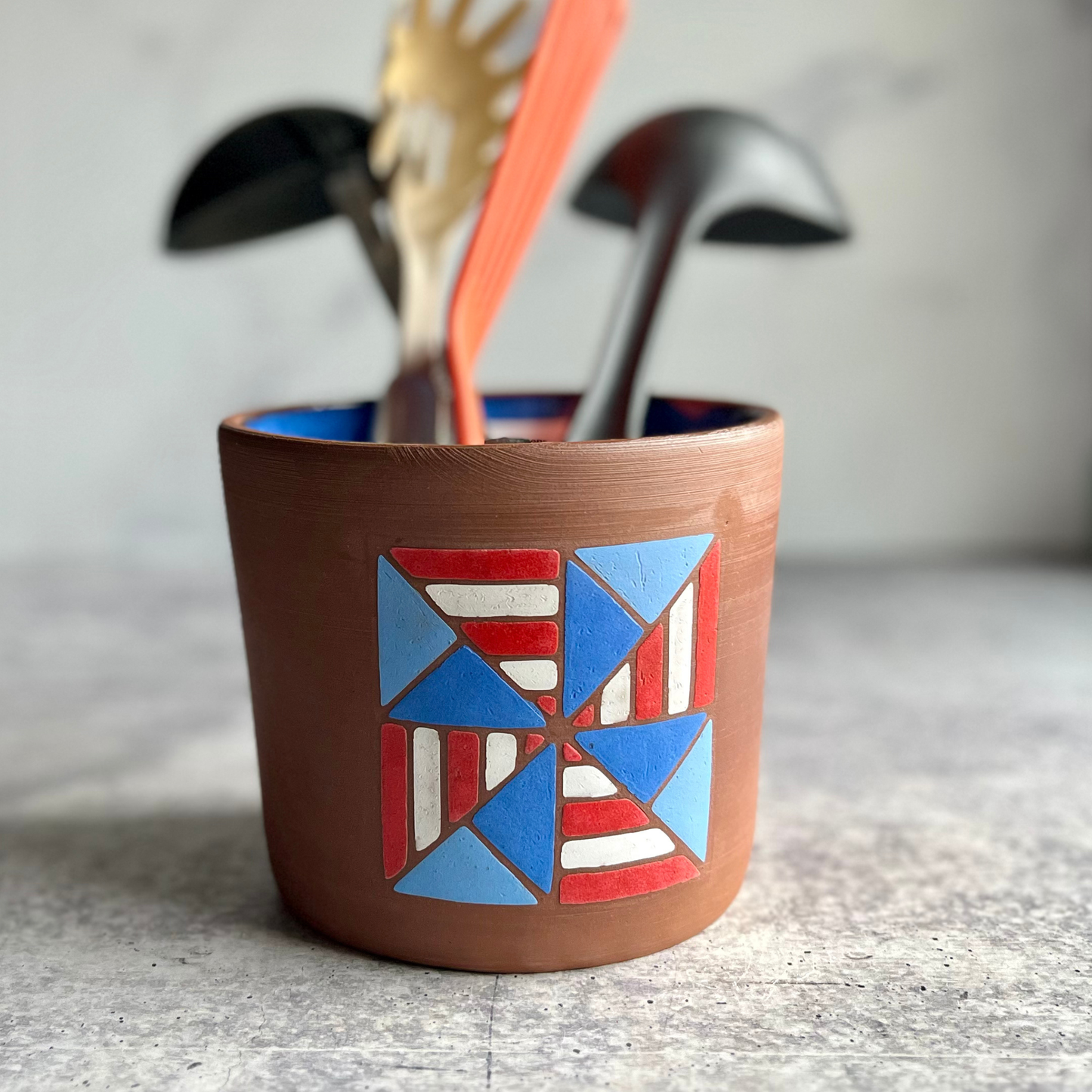 Ceramic utensil holder with geometric design on a textured surface