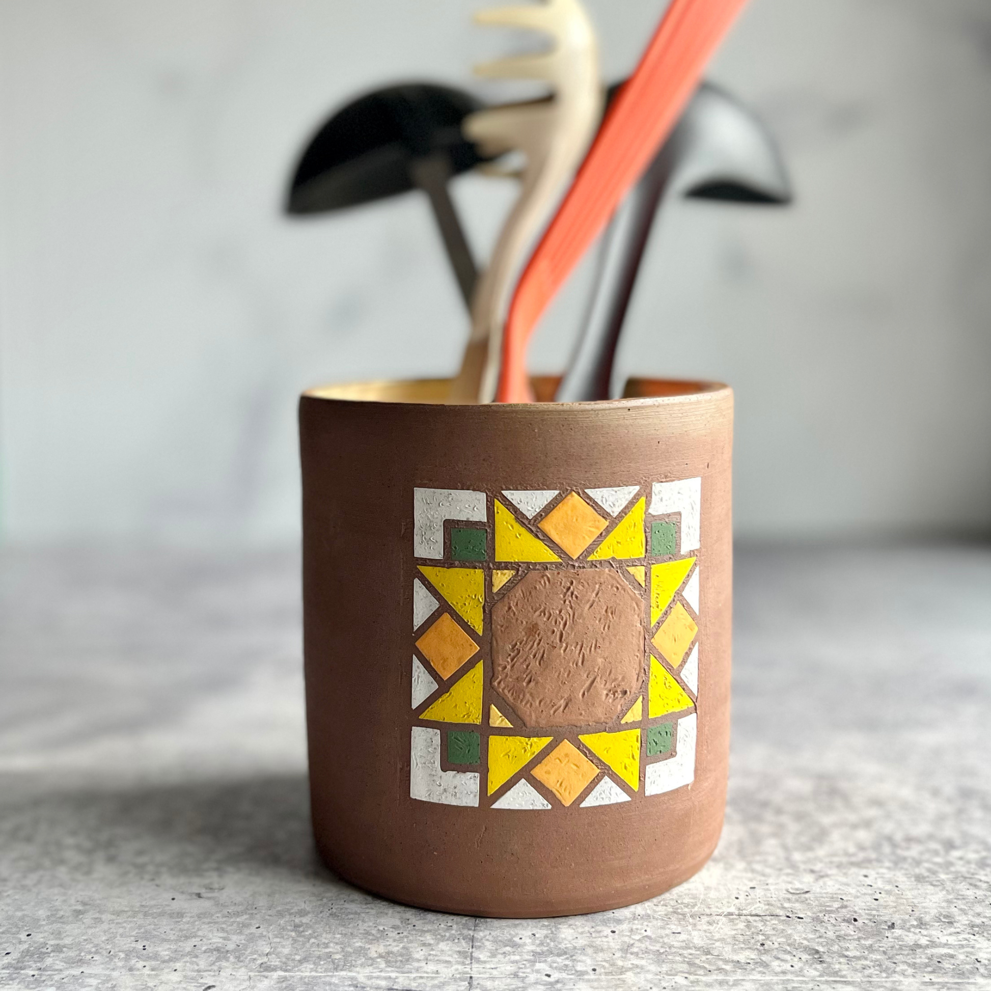 Ceramic utensil holder with geometric design on a textured surface