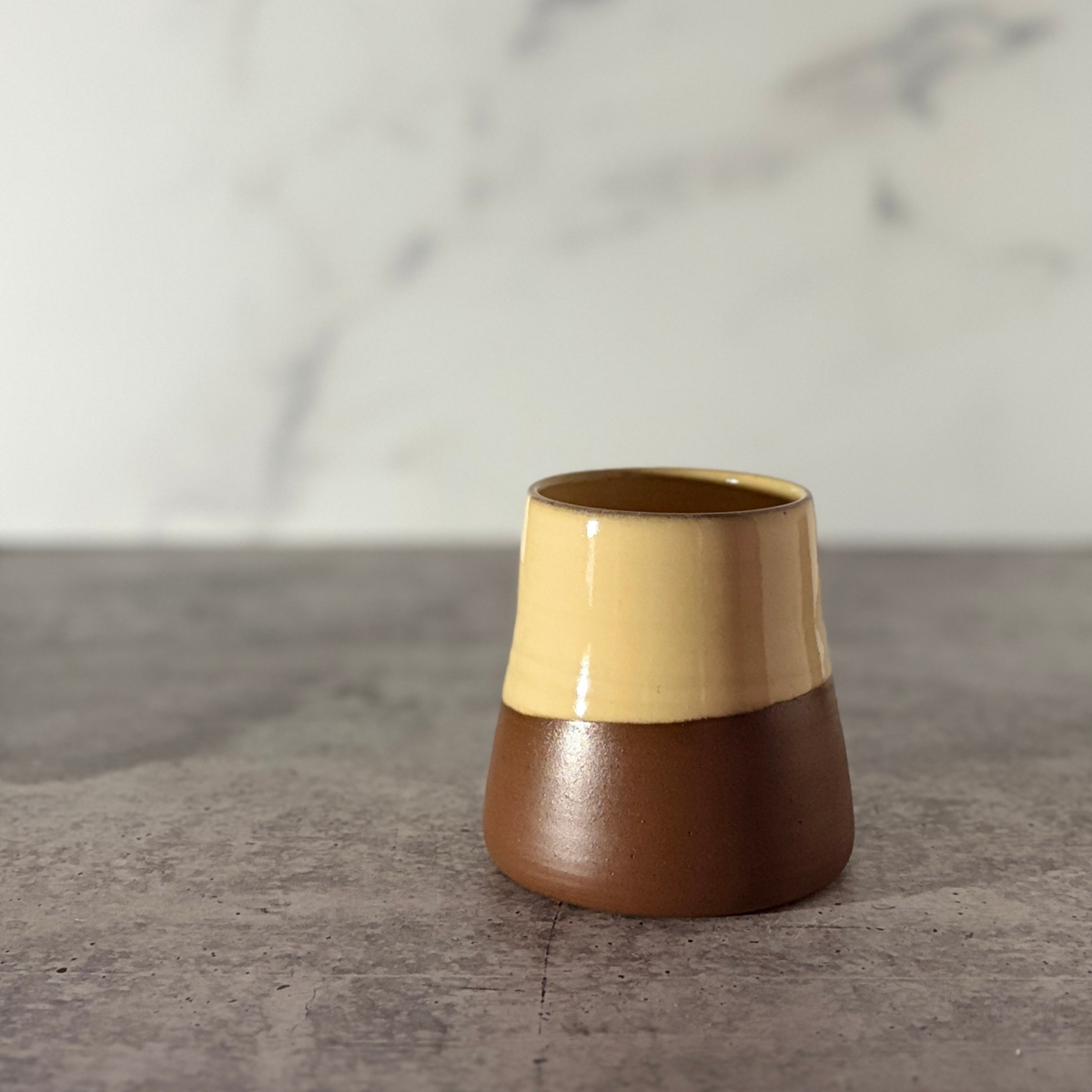 Cone shaped bud vase. Buttery yellow glaze partially down outside showing chocolate clay.